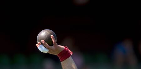 Man Lifting Shot Put at a Track and Field Meetの写真素材