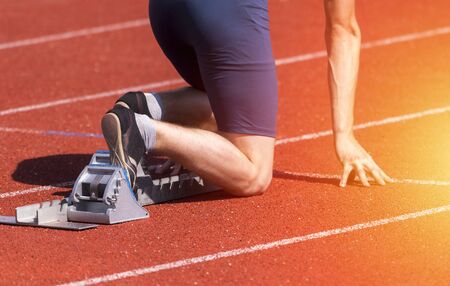 Runners preparing for race at starting blocks. Sunny dayの写真素材