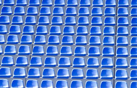 Empty blue plastic chairs in a row at the football stadiumの写真素材