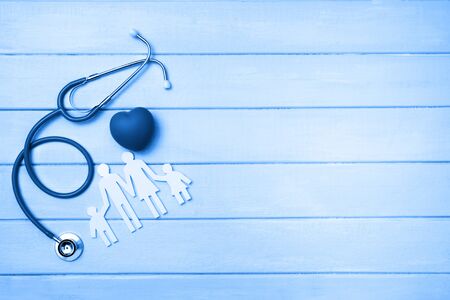 Medical Insurance Concept. Family cutout and Stethoscope on wooden background. Blue tonned.の写真素材