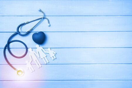 Medical Insurance Concept. Family cutout and Stethoscope on wooden background. Blue tonned.の写真素材