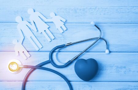 Medical Insurance Concept. Family cutout and Stethoscope on wooden background. Blue tonned.の写真素材