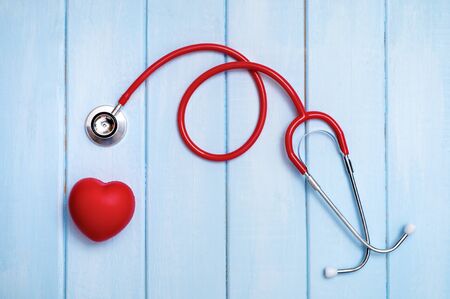 Red heart with stethoscope on blue wooden background. Copy space. Valentines day.の写真素材