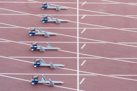 Athletic start block on dark red tartan trackの写真素材