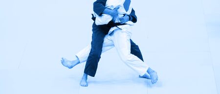 Two judo fighters in white and blue uniform.  Blue color filtrの写真素材