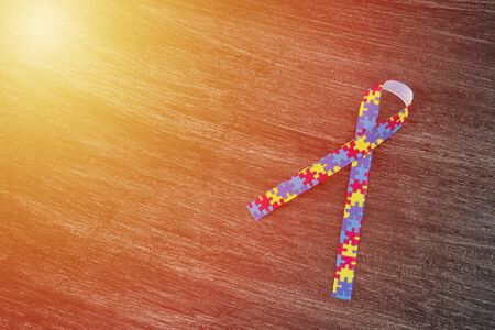 World Autism awareness and pride day or month with Puzzle pattern ribbon on wooden background.の写真素材
