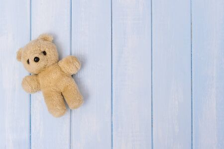 Small teddy bear on blue pastel wooden background, top viewの写真素材