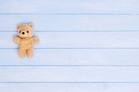 Small teddy bear on blue wooden background, top view