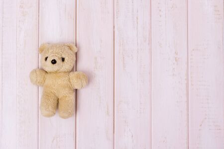 Small teddy bear on pink wooden background, top viewの写真素材