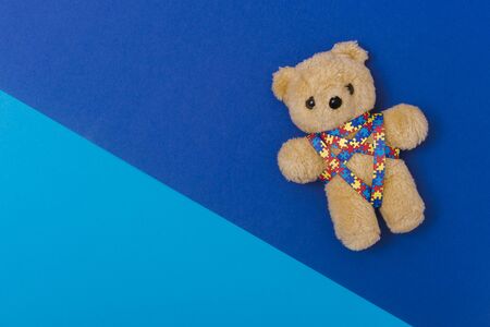 World Autism Awareness day, mental health care concept with teddy bear and ribbon puzzle pattern. On blue backgroundの写真素材