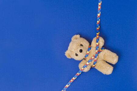 World Autism Awareness day, mental health care concept with teddy bear and ribbon puzzle pattern. On blue backgroundの写真素材
