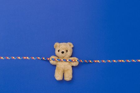 World Autism Awareness day, mental health care concept with teddy bear and ribbon puzzle pattern. On blue backgroundの写真素材