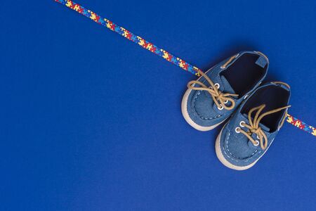 World Autism Awareness day, mental health care concept with blue baby shoes and ribbon puzzle pattern. On blue backgroundの写真素材