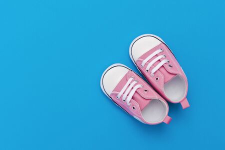 Pink baby shoes on a blue background with space for text. Top viewの写真素材