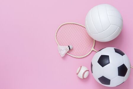 Assorted sports equipment including a basketball, soccer ball, volleyball, baseball, badminton racket on a pink backgroundの写真素材