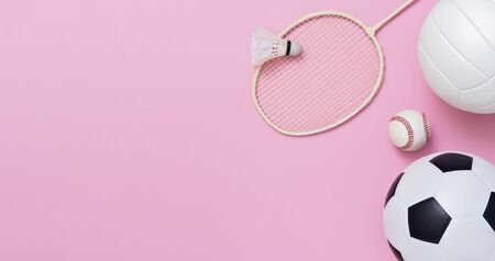 Assorted sports equipment including a basketball, soccer ball, volleyball, baseball, badminton racket on a pink backgroundの写真素材
