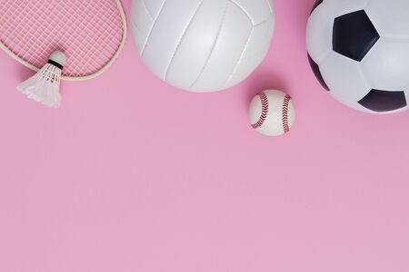 Assorted sports equipment including a basketball, soccer ball, volleyball, baseball, badminton racket on a pink backgroundの写真素材