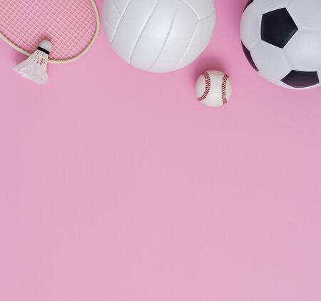 Assorted sports equipment including a basketball, soccer ball, volleyball, baseball, badminton racket on a pink backgroundの写真素材