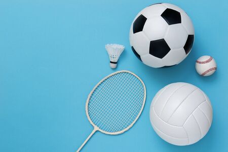 Assorted sports equipment including a basketball, soccer ball, volleyball, baseball, badminton racket on a light blue backgroundの写真素材