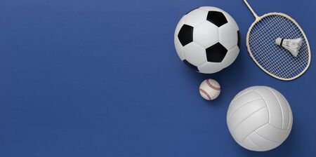 Assorted sports equipment including a basketball, soccer ball, volleyball, baseball, badminton racket on a blue backgroundの写真素材
