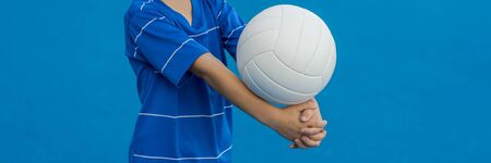 Boy playing volleyball isolated in blue.の写真素材