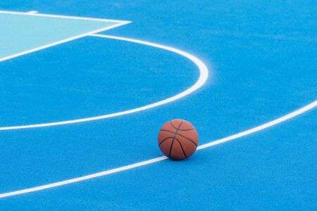 Orange basketball on blue court of gymnasium sport floorの写真素材