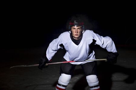Hockey player. Portrait of a handsome ice-hockey player with hockey stickの写真素材