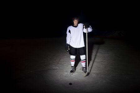 Hockey player. Portrait of a handsome ice-hockey player with hockey stickの写真素材