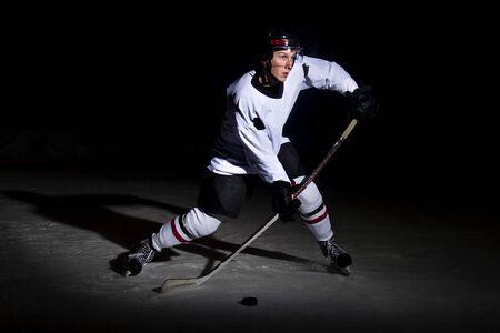 Ice hockey player in action kicking with stickの写真素材