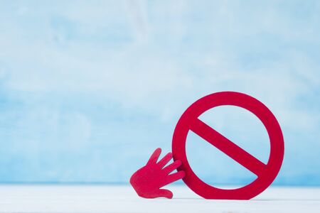 Red forbidden sign and hand  on blue background.の写真素材