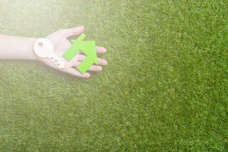 Hand hold house and key against green field, viewed from the top.の写真素材