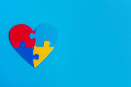 Puzzle pieces in form of heart, isolated on blue background. World Autism Awareness Day Conceptの写真素材