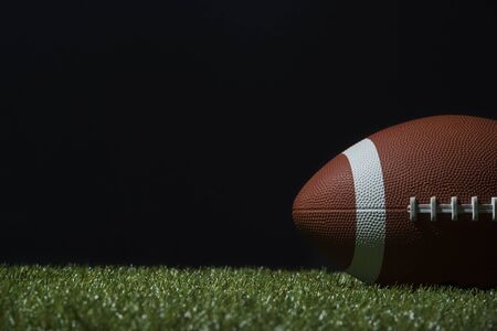 American football on green grass, on black backgroundの写真素材