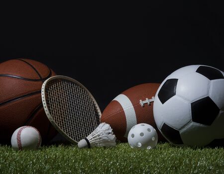 Sports equipment, rackets and balls on green grass with black background and copy space.の写真素材