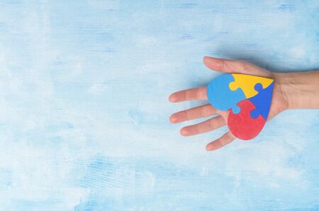 Hand Holding Colorful Heart On Blue Background. World Autism Awareness Day Conceptの写真素材