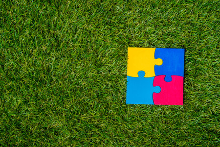 Colorfull puzzles piece on green grass background. World Autism Awareness Day Concept