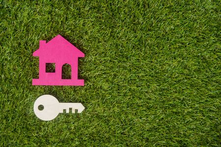Wooden house and key on artificial green grass. Property investment and house mortgage concept. Copy space.の写真素材