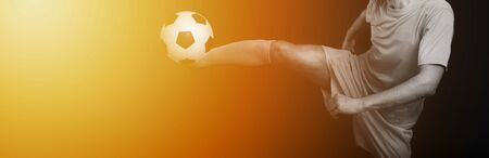 Close up legs and soccer shoe of football player in action kicking ball isolated on black background.Yellow filterの写真素材