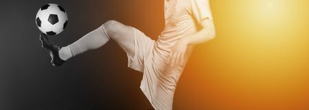 Close up legs and soccer shoe of football player in action kicking ball isolated on black background.Yellow filterの写真素材