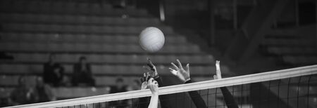 Girl Volleyball player and setter setting the ball for a spiker during a game. Team sport. Black and white filter.の写真素材