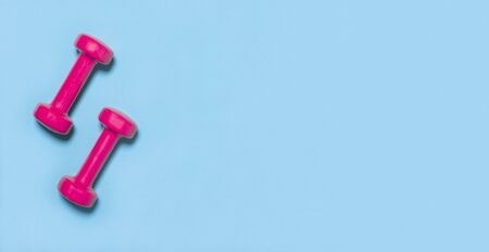 Pink dumbbells isolated on blue backgroundの写真素材