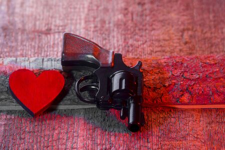 Bad love Background. Red Heart and gun On A Wooden Backgroundの写真素材