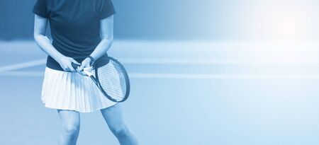 Close up of woman is holding tennis racket on hard tennis court. Blue filterの写真素材