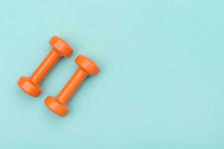 Orange dumbbells isolated on green backgroundの写真素材