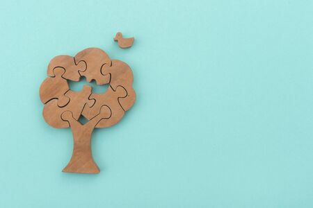 Wooden tree and bird puzzle over green backgroundの写真素材