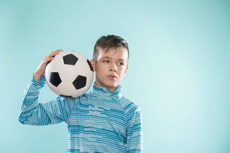 Boy posing with soccer ball on blue studio background.の写真素材