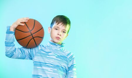 Young basketball player posing with a ball in his hand isolated on blue background.の写真素材