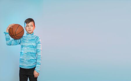 Young basketball player posing with a ball in his hand isolated on blue background.の写真素材