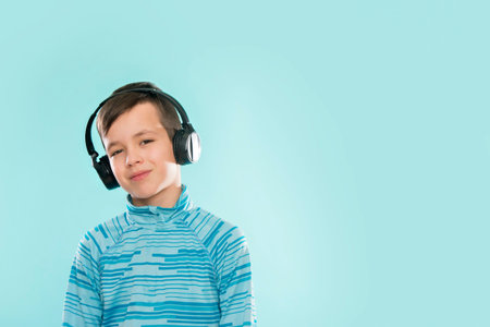 Kid enjoying music on his headphones, listening to music. Handsome young stylish kid in headphones...