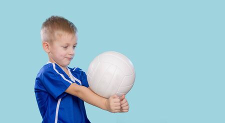 Happy little kid in a blue shirt with a ball for volleyball. Physical, sport.の写真素材